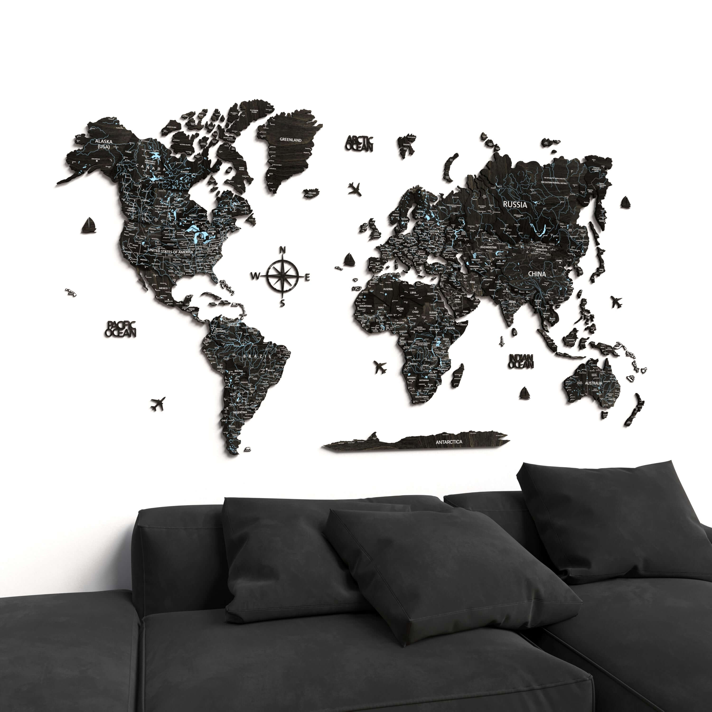 Black Wood World Map displayed on a wall above a modern sofa, showcasing elegant home decor for travel lovers.