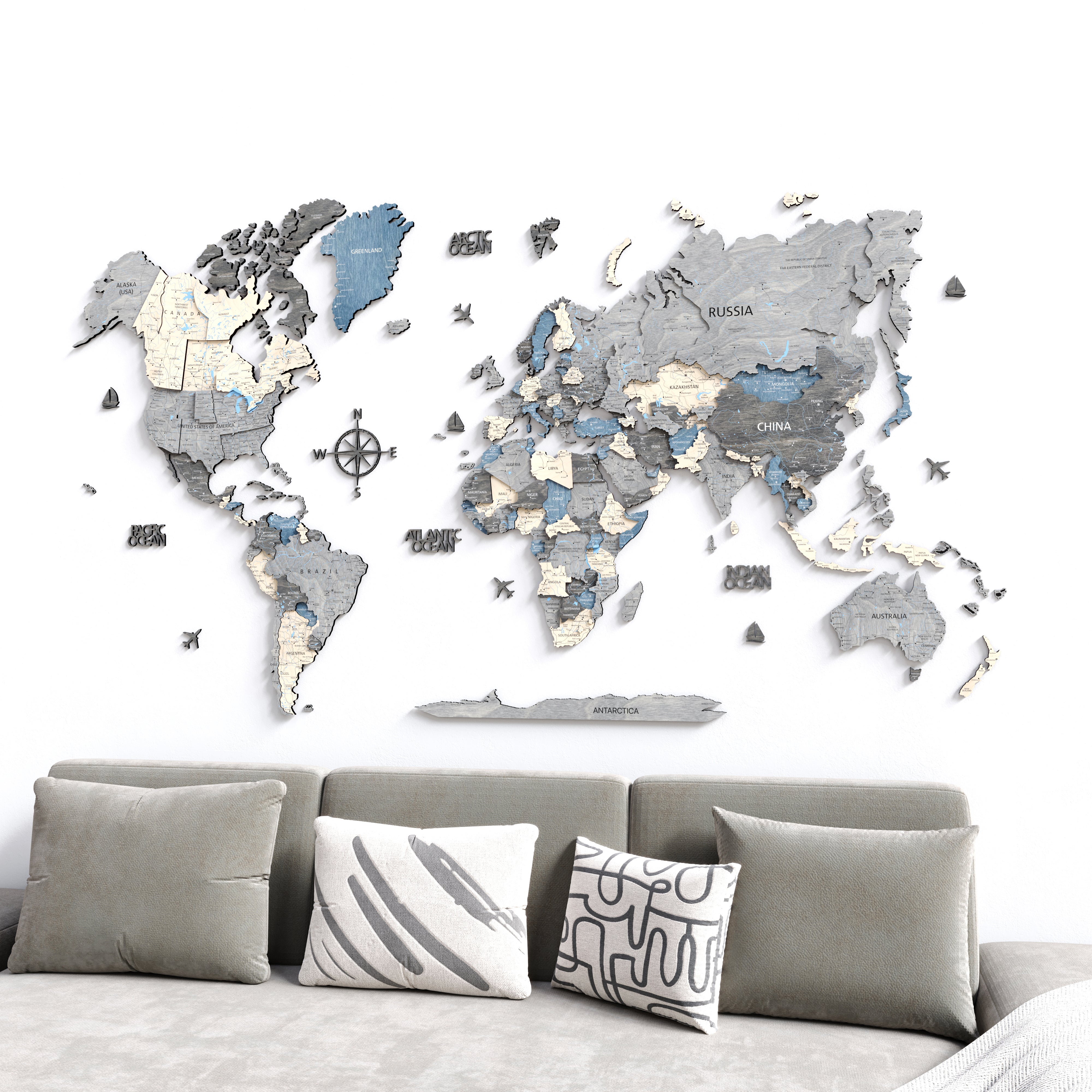 3D wooden world map displayed on a wall above a modern gray sofa, showcasing intricate wooden continents and details.