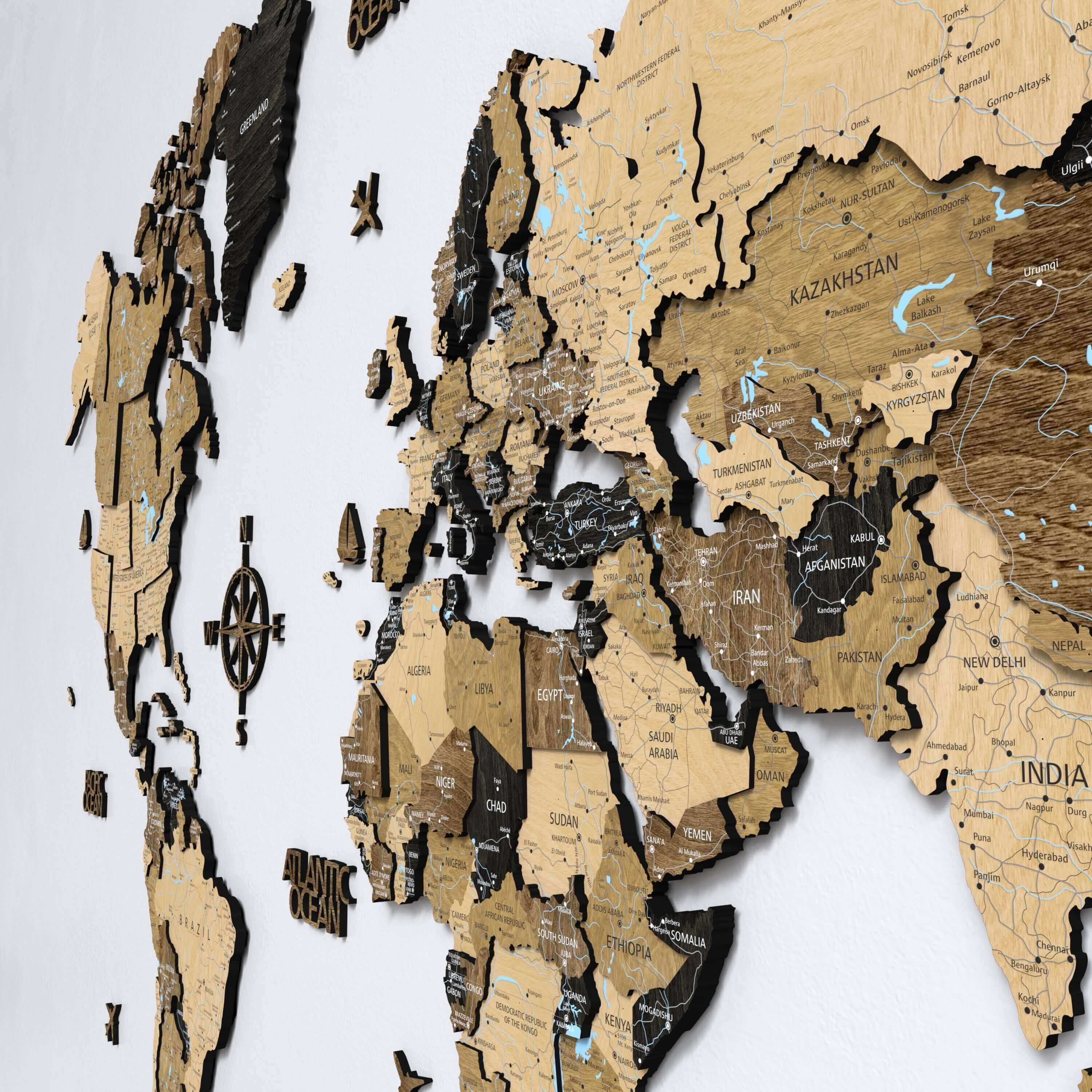 A modern living room showcasing a dark brown 3D wooden world map with printed country names. This push pin map adds depth and texture to the wall, making it a perfect piece of home decor or apartment wall art for travel enthusiasts.